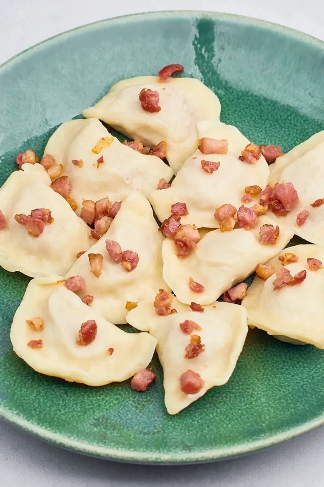 Pierogi okraszone skwarkami na zielonym talerzu